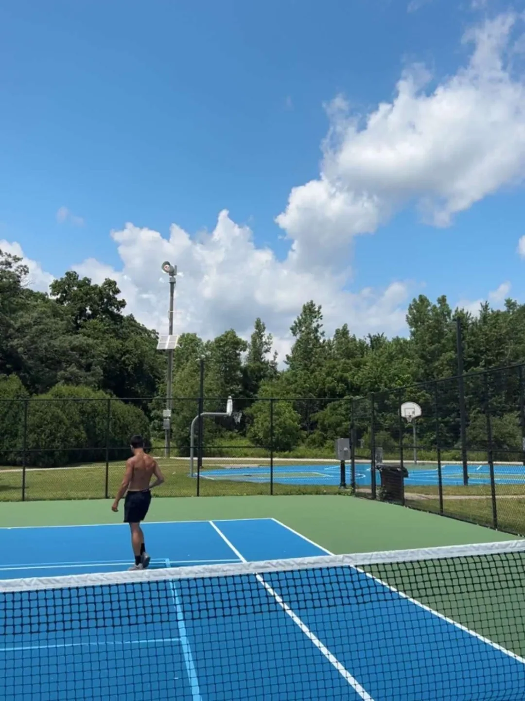 A bright blue outdoor court and an afternoon outside.