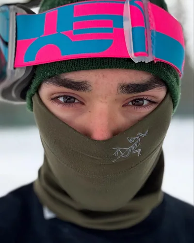 A close portrait with a face covering and pink goggles.