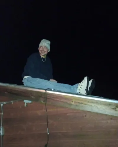 Alex sitting on a fence at night.