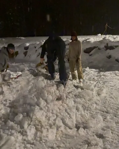A group walking through deep snow at night.