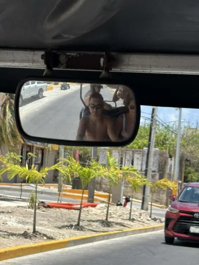People reflected in a vehicle’s rearview mirror.