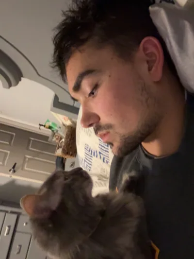 Alex leaning toward a cat indoors.