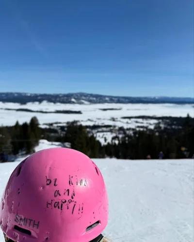 A pink helmet in the foreground of a snowy panorama.