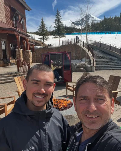 Alex and a companion smiling at a snowy resort.