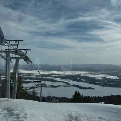 A chairlift above snow-covered hills and a distant valley.