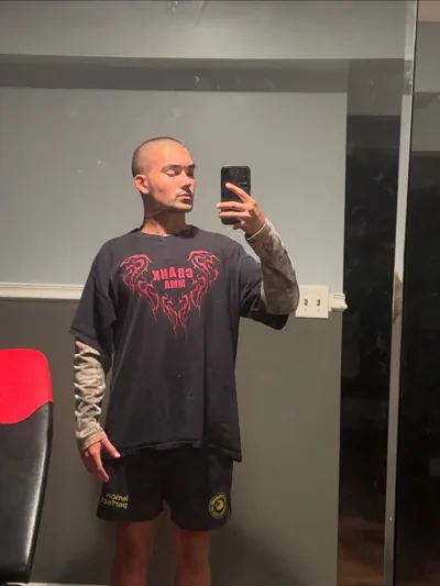 Alex taking a mirror portrait in a dark graphic top.