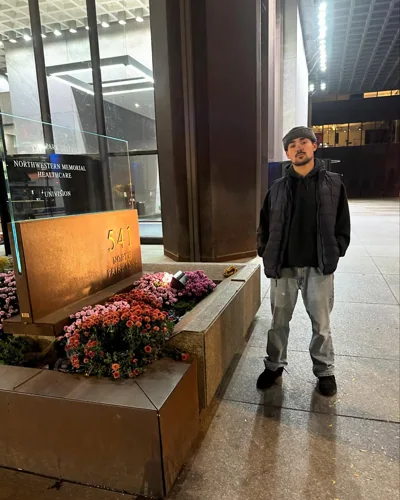 Alex outside a Chicago building beside flowers.