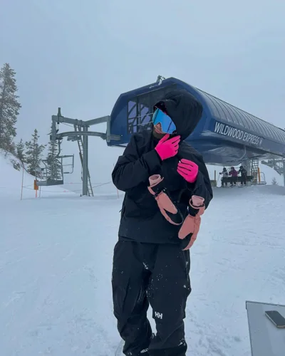 In winter gear beside the lift during snowfall.