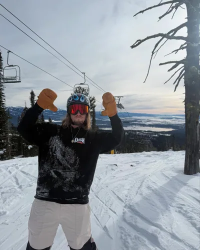 A rider with both mittens raised on the mountain.