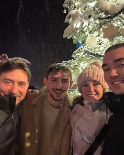 Friends gathered outside beneath snow-covered trees.