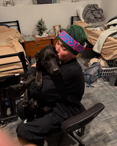 Alex with a dog indoors, still wearing snow gear.
