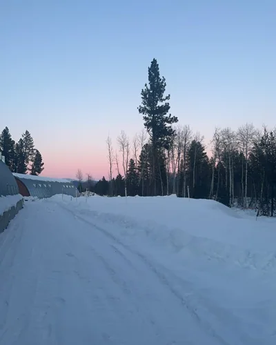 A snowy road beneath a soft pink sky.