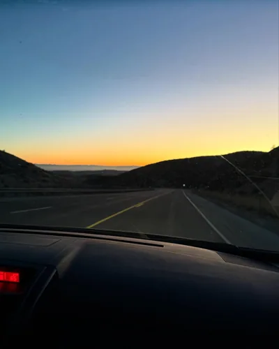 A road toward a sunset, seen from a vehicle.