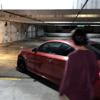 A photograph beside a red car in a parking garage.