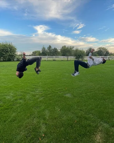Two people photographed mid-flip on a green lawn.