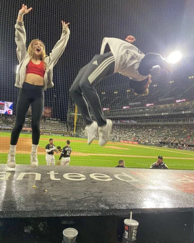 A person mid-flip at a baseball stadium, beside a friend.