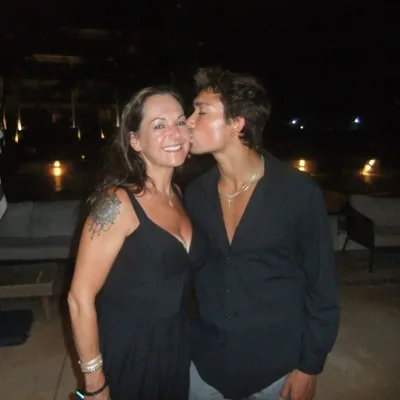 Alex kissing a companion on the cheek in a night-time portrait.