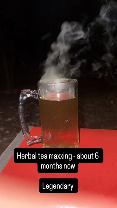 Steam rises from a clear mug on a red outdoor surface at night.